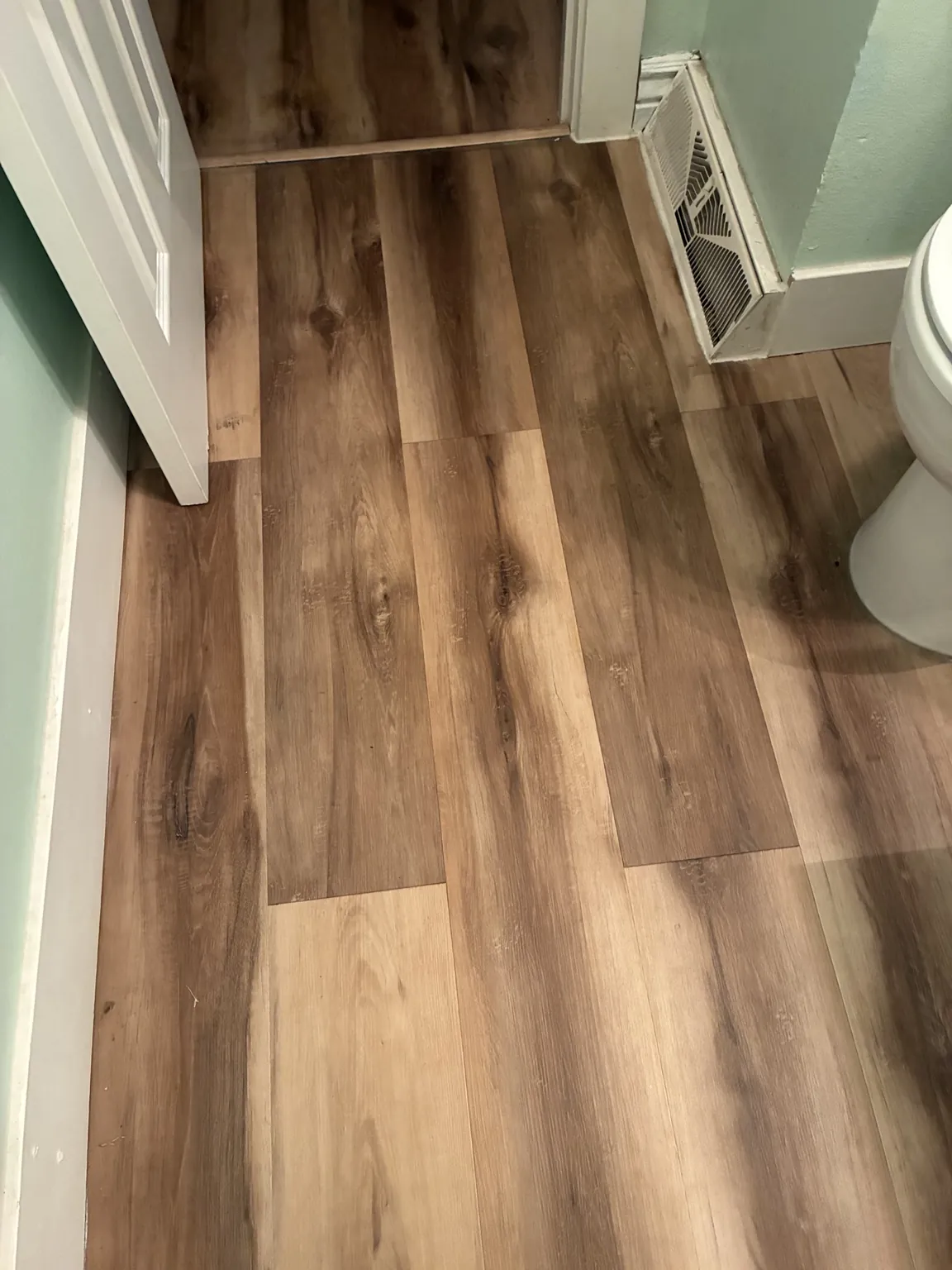 Installed bathroom flooring around the doorway and floor vent